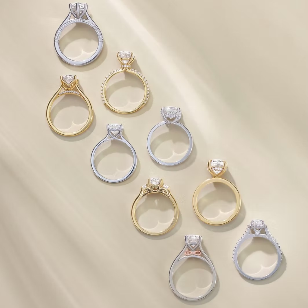 Collection of diamond solitaire engagement rings in gold and white gold settings displayed on neutral background