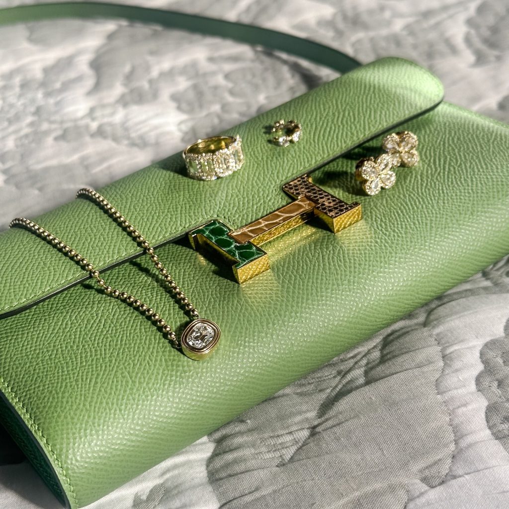 Diamond rings and jewelry displayed on green leather jewelry case with decorative fabric background