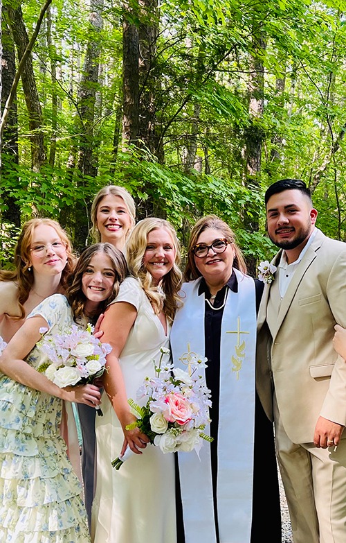 Reverend Susie with wedding party and newlyweds in outdoor garden setting