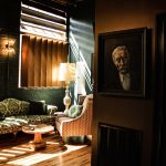 Elegant lounge with vintage seating, backlit shutters, and classical portrait creating intimate rehearsal dinner ambiance