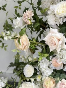 Romantic pastel floral arrangement with blush and white roses, pink dahlias, hydrangeas, and fresh greenery