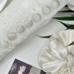 White fabric with embroidered buttons beside vintage photo and silk fabric detail