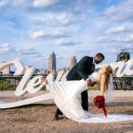 Groom dipping bride with flowing white wedding dress against Cleveland skyline