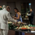 Wedding guests being served at buffet table with elaborate food display