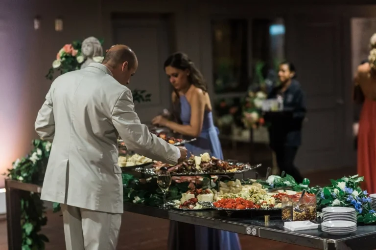 Wedding guests being served at buffet table with elaborate food display