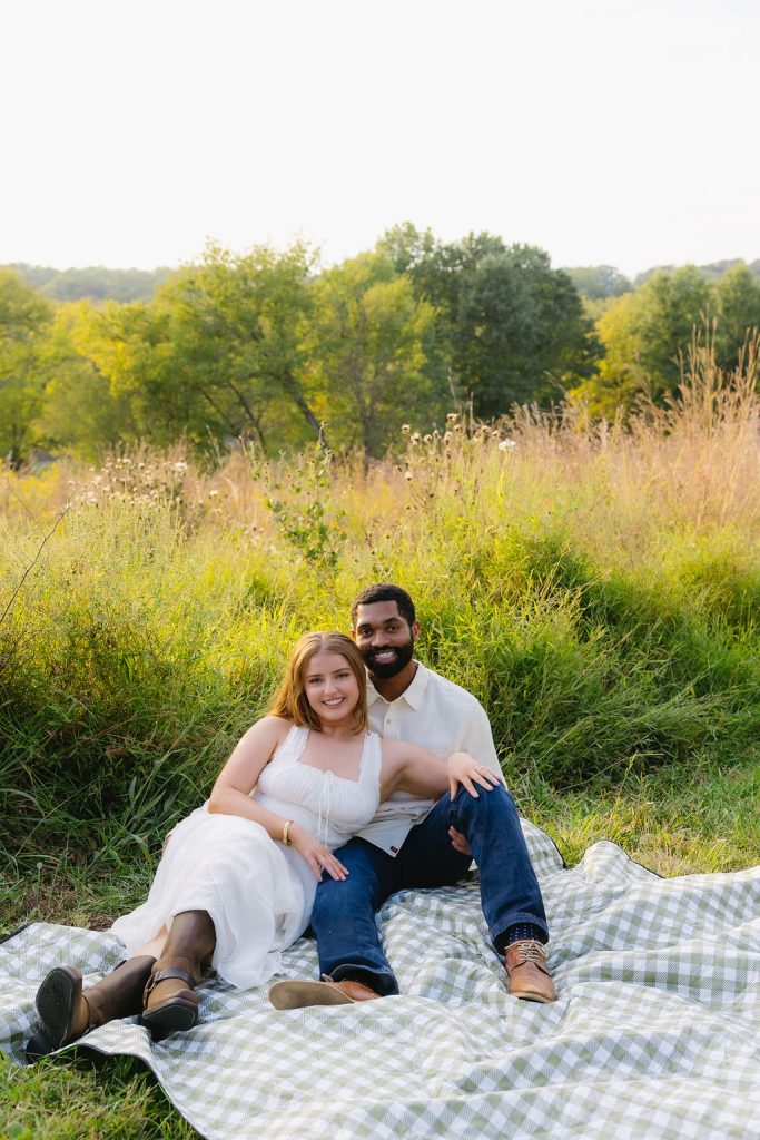 Engaged couple embracing on picnic basket in Queeny Park captured by Mad Land Photography.