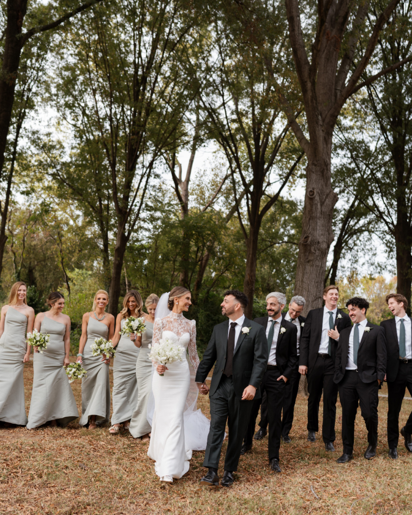 Cathy and Charlie walking with their wedding party outdoors, bridesmaids in neutral dresses and groomsmen in classic black suits