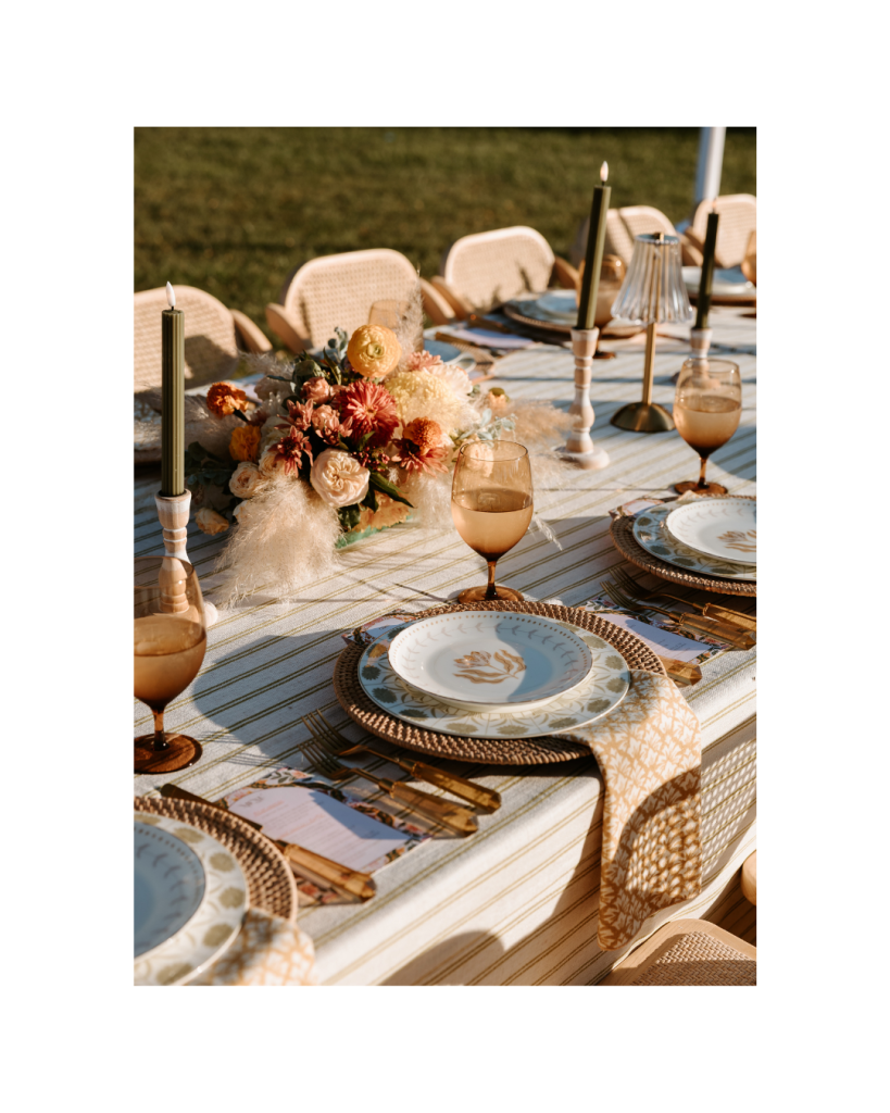 A detailed view of the tablescape with layered place settings, textured linens, candles, and floral arrangements.