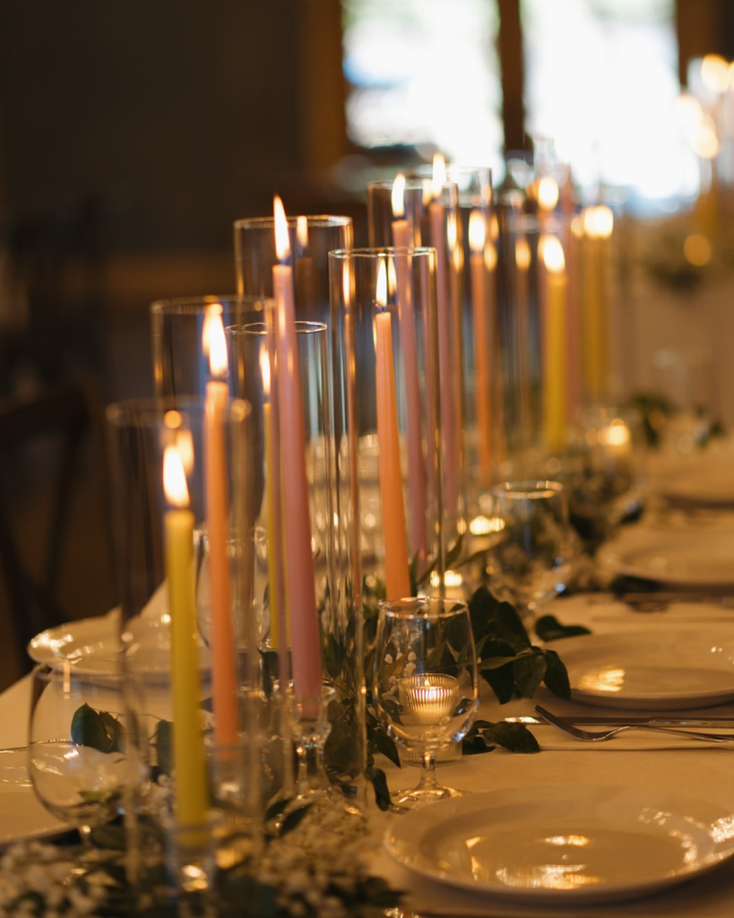 Reception tables decorated with tall colorful taper candles creating a romantic glow at Union Exchange wedding reception