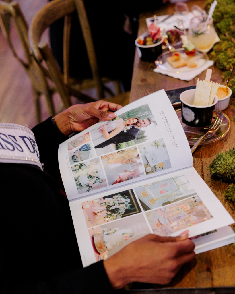 Guest seated at reception table with Wed Society Book of Weddings magazine open at King Cole Farm in Dover, Delaware.