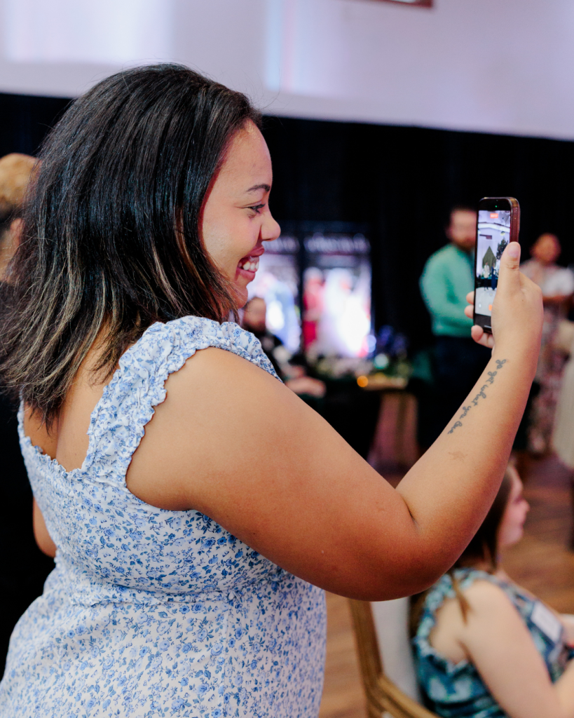 The Bridal Bestie content creator capturing behind-the-scenes footage on mobile phone during Wed Society Delaware Book of Weddings Release Event at King Cole Farm in Dover, Delaware.