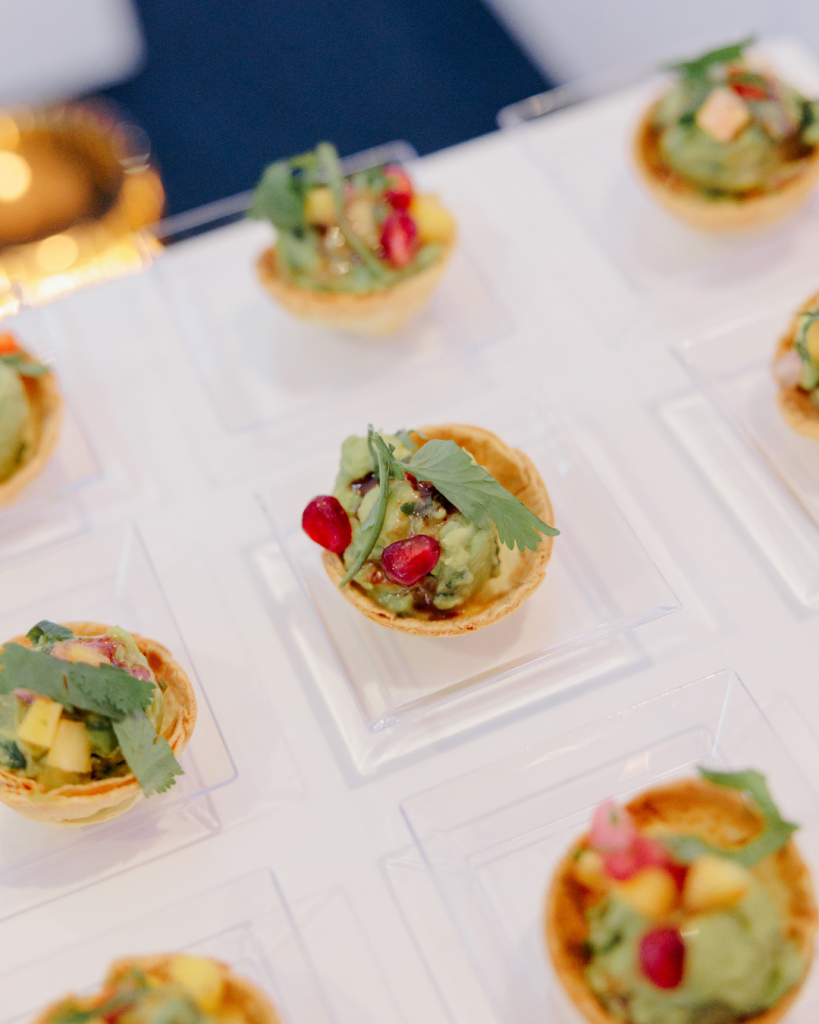 Mini tart appetizers prepared by Savora Catering & Events topped with avocado, herbs, and pomegranate seeds at Delaware wedding industry event.
