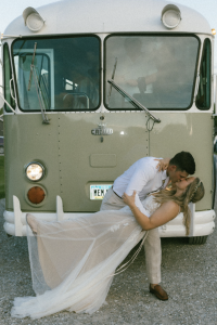 couple kissing in front of their wedding transportation