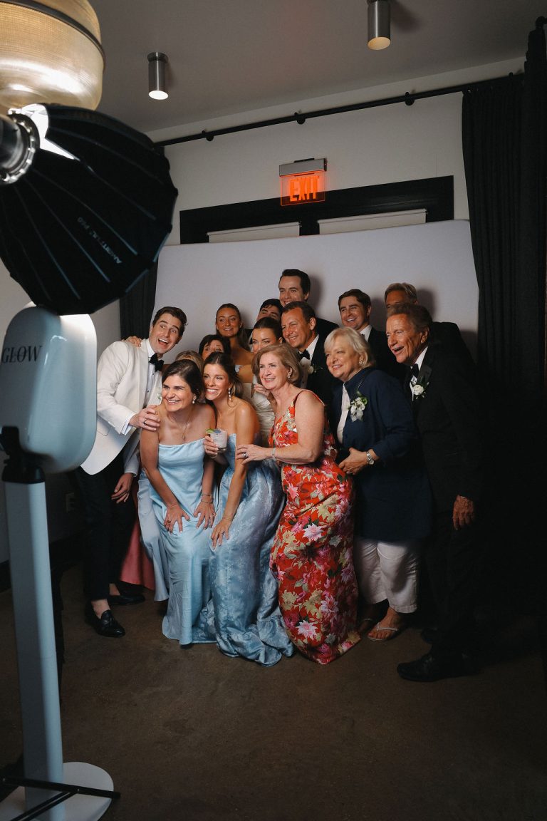 Groom with wedding guests in photo booth with crisp white background provided by Glow Booth STL.