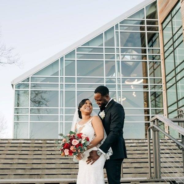 Bride and Groom posing in front of windowed wedding venue