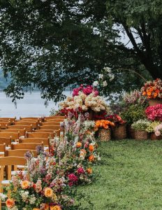 bright colored florals lining wedding aisle at outdoor wedding ceremony