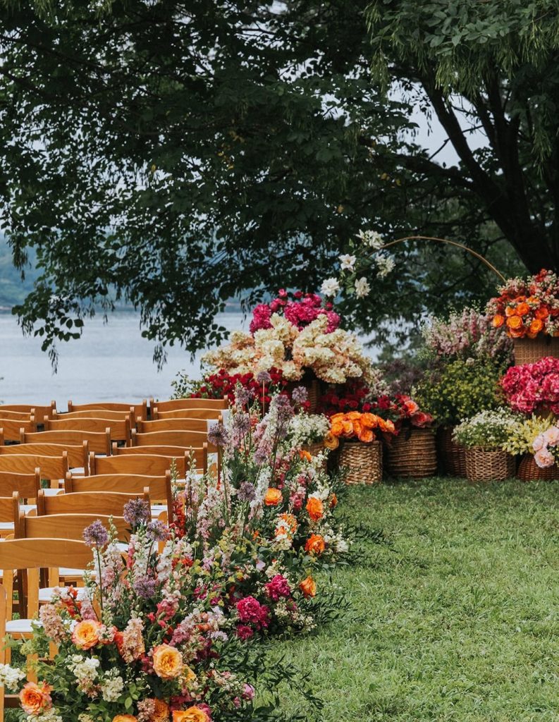 bright colored florals lining wedding aisle at outdoor wedding ceremony