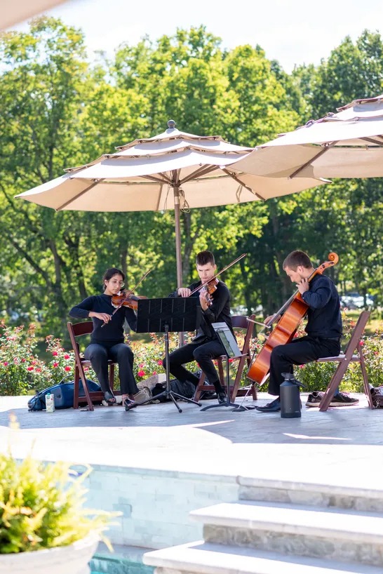 String Trio playing at outdoor wedding ceremony by pool
