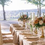 Long Rectangular reception table with gold decor accents and lush flower vases