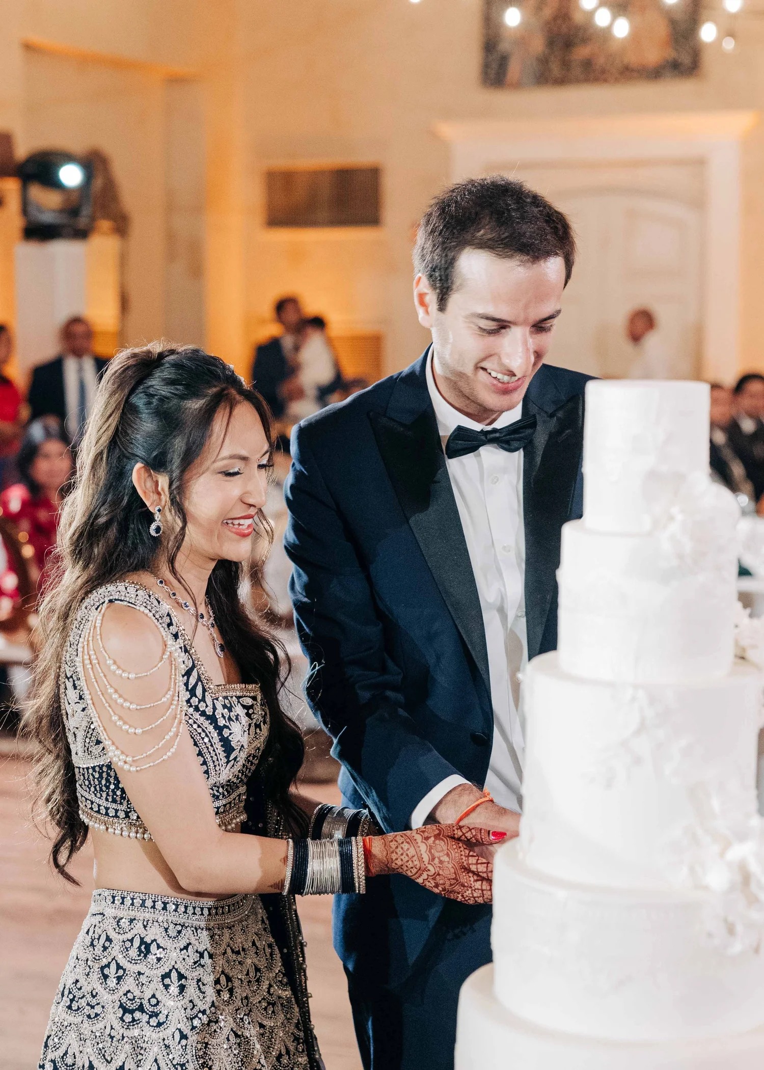 Couple cutting white four tier wedding cake at wedding reception