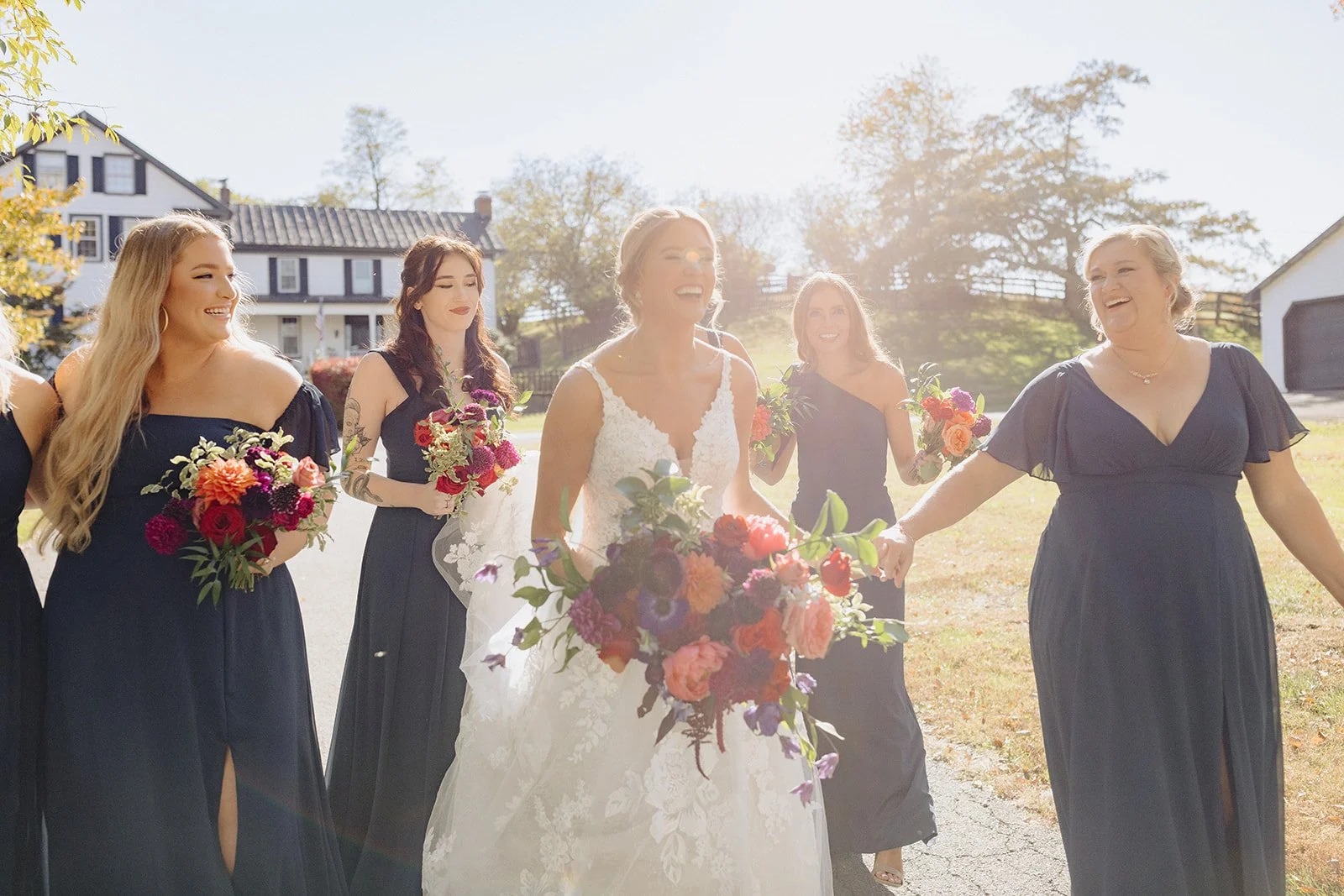 Bride and Bridesmaids walking to outdoor ceremony space with their deep red flowers