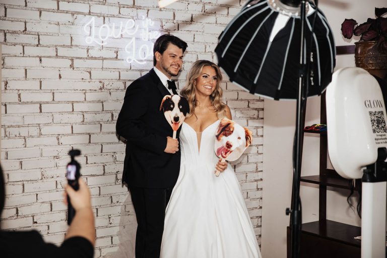 Couple holding props in a photo booth created by Glow Booth STL