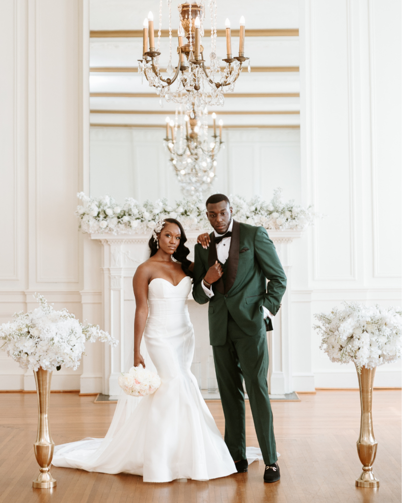 Bride and groom Zee and Bobby posing together in an elegant ballroom with white walls and chandeliers at The Hotel Concord