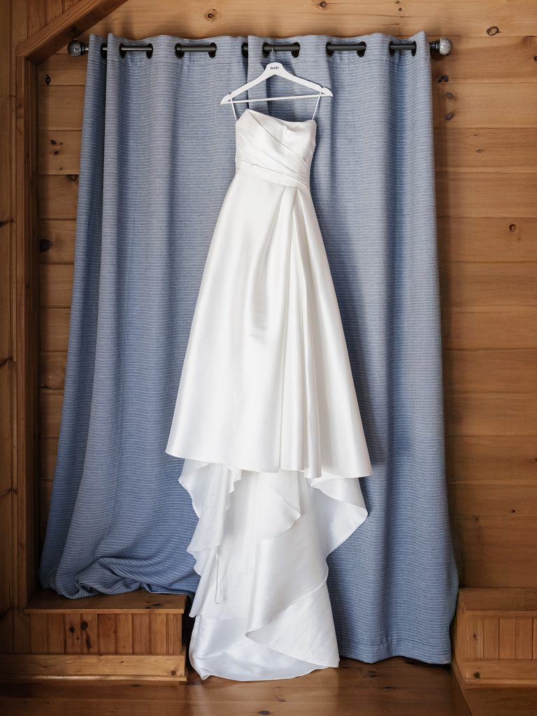 elegant white wedding dress handing on window sill during getting ready photos