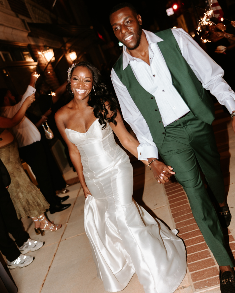 Bride and groom dancing and celebrating at their reception with energetic lighting and guests around them