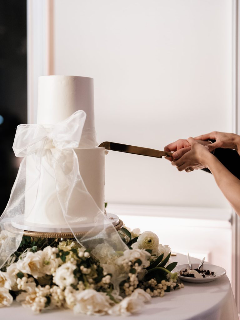 Husband and Wife cutting wedding take with white tied how