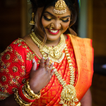 inidan bride in a vibrant orange dress with gold jewelry