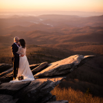 bride and groom on a mountain with a beautiful sunset behind them