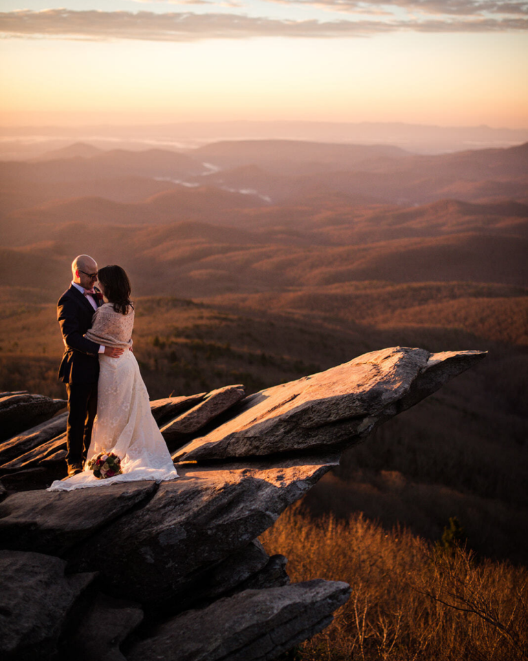 bride and groom on a mountain with a beautiful sunset behind them