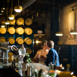 bride and groom kissing in a bar with whisky barrels behind them