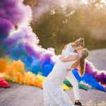LGBTQ+ couple kissing with rainbow cloud and trees behind them