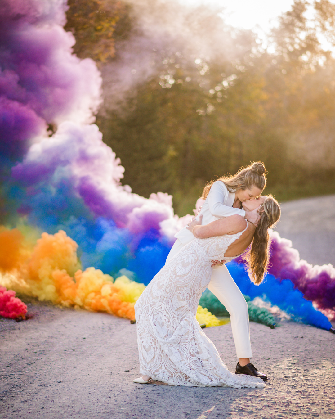 LGBTQ+ couple kissing with rainbow cloud and trees behind them