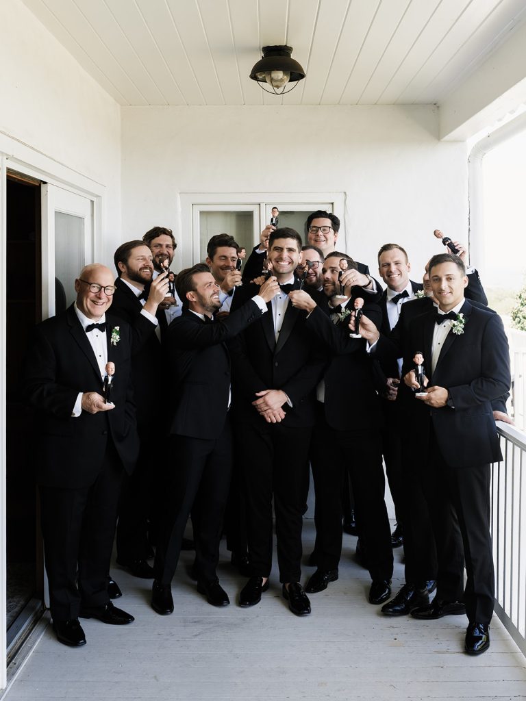 silly photo of groom and groomsmen on balcony before wedding ceremony