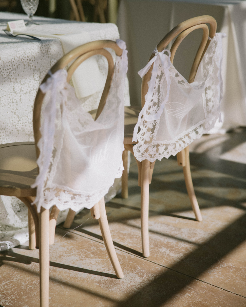 Lace bride and groom signs draped behind chairs at the reception