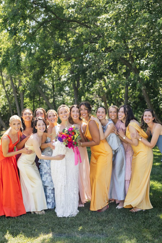 Bride with bridesmaids in colorful dresses holding vibrant bouquets at Eastern Shore waterfront wedding
