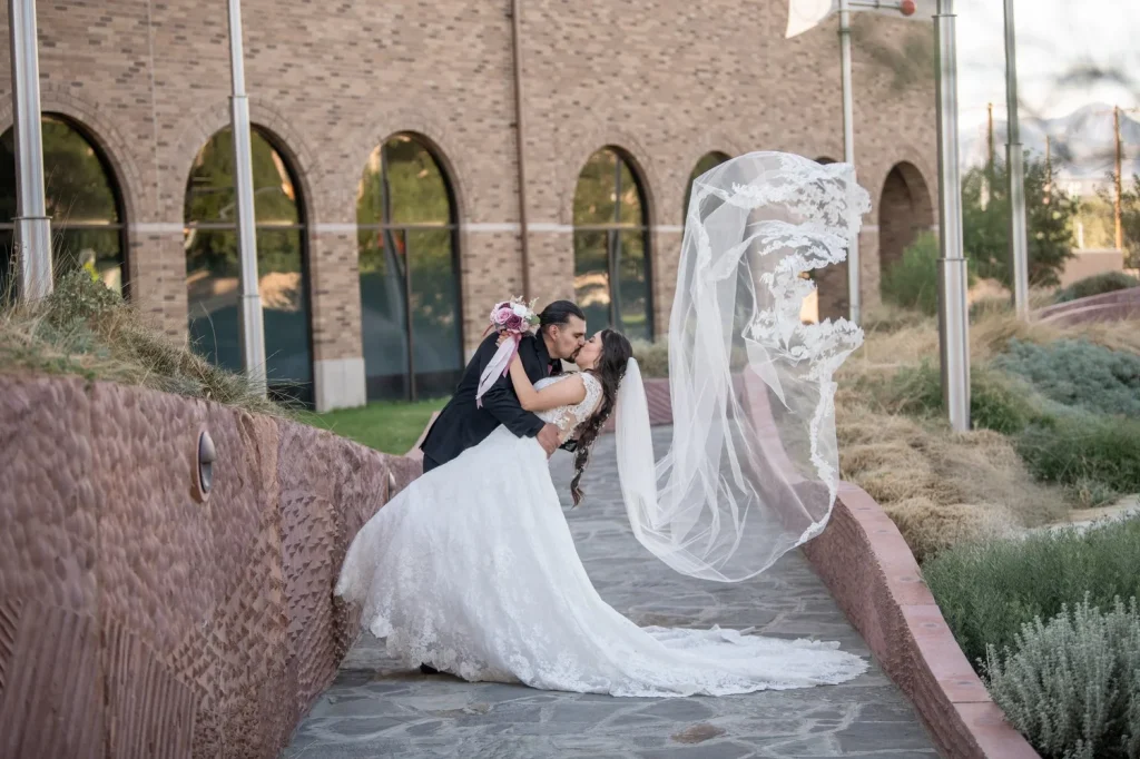 bride and groom dip kiss with veil in air