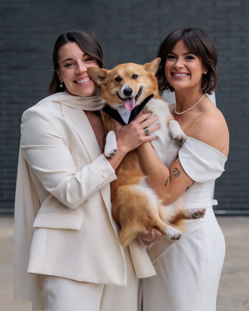 Laura & Tory holding their dog on their wedding day