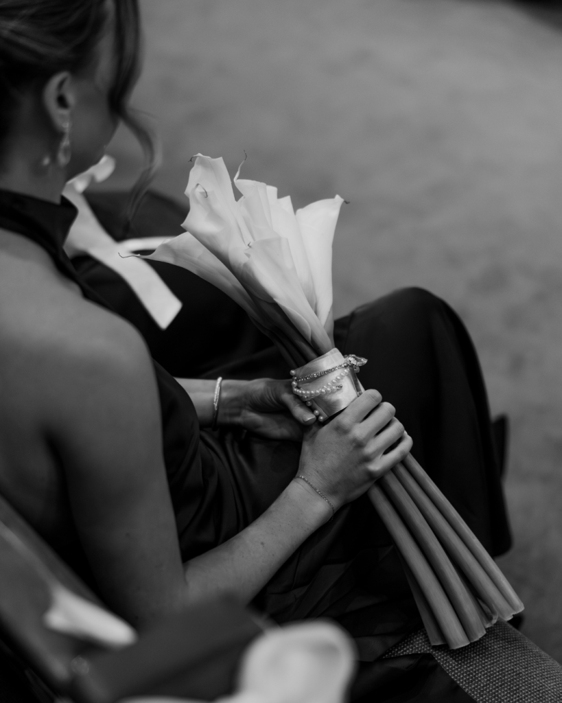 Close up black and white photo of the bride holding a bouquet of white flowers during the ceremony