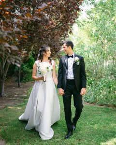 Bride and groom walking holding hands through nature