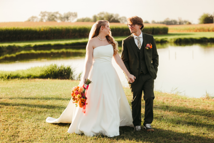 Bride and groom walking hand in hand along pond at golden hour during outdoor Eastern Shore Maryland farm wedding.