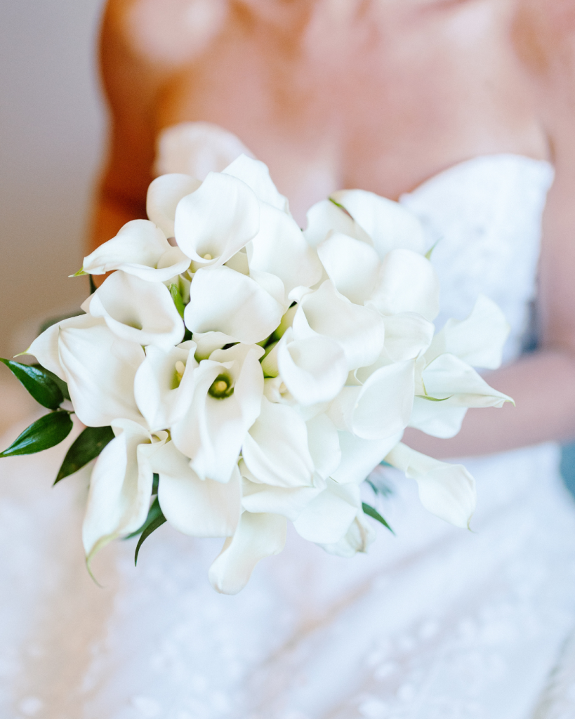 Bride holding white calla lily bouquet with soft ribbon detail at Rehoboth Beach Country Club wedding in coastal Delaware.