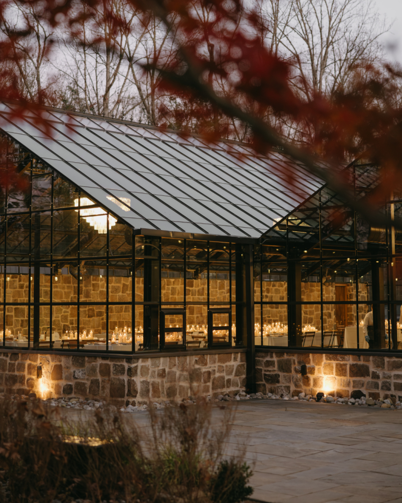 Exterior view of Morning Glory Farms greenhouse at dusk in winter with warm light glowing from inside