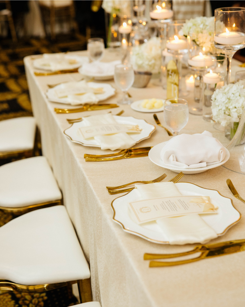 Wedding tablescape with gold flatware, candles, and soft linens styled for Charlotte luxury wedding