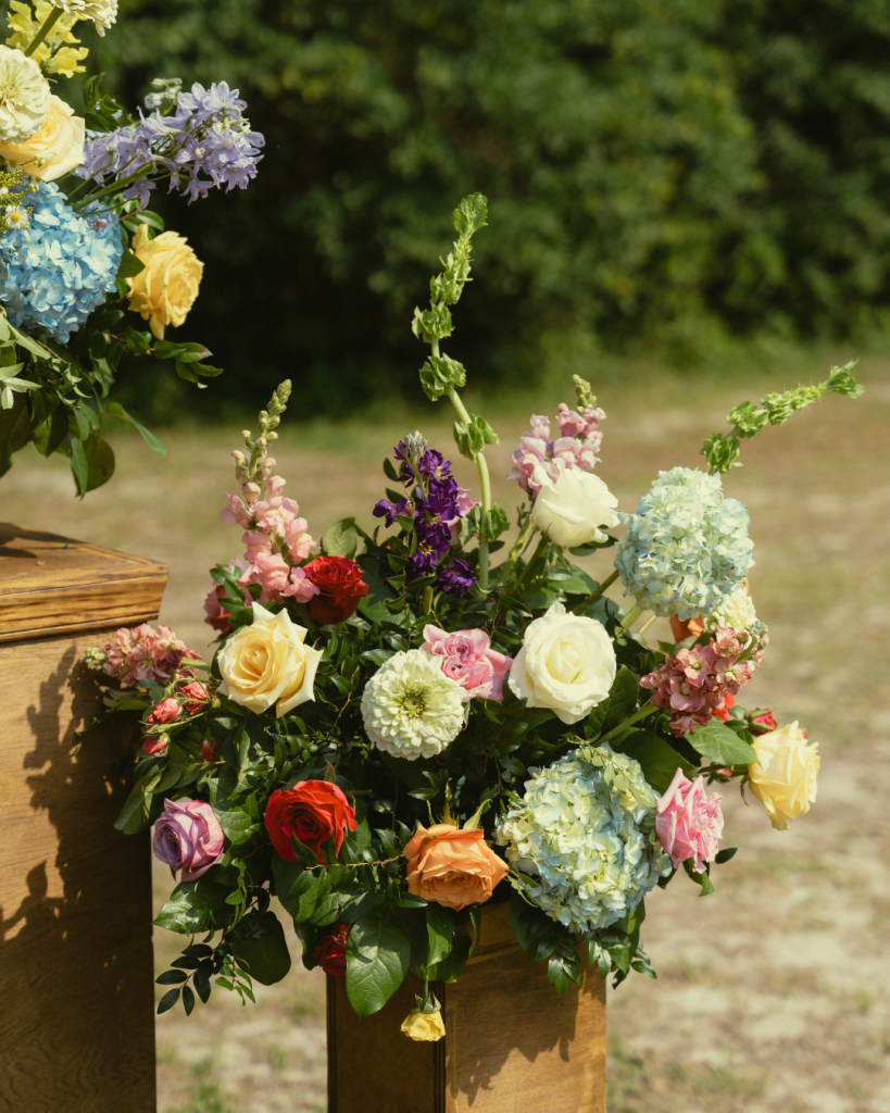 Ceremony florals in bright seasonal colors arranged on wooden structure at coastal Delaware wedding
