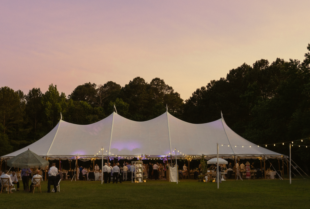 Sailcloth tent glowing at sunset during outdoor reception at Ocean View Delaware summer wedding