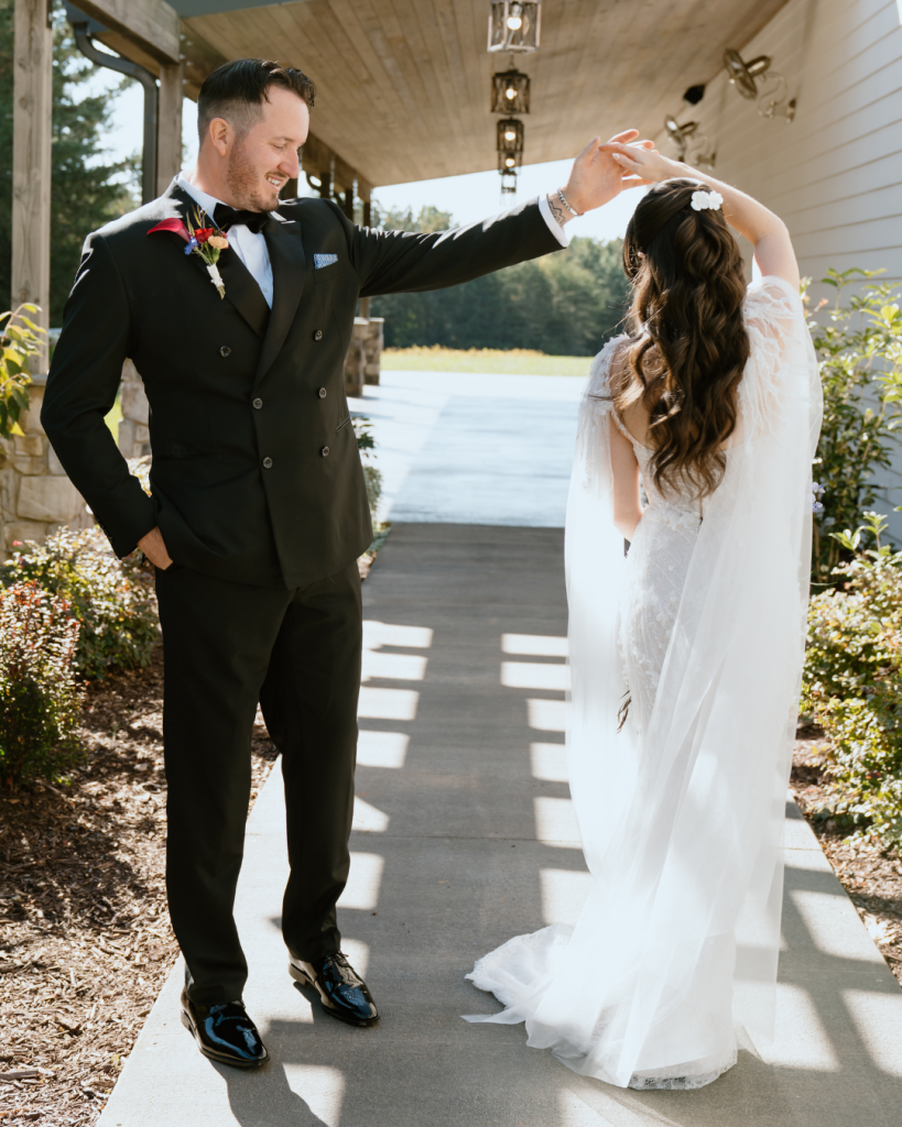 Groom twirling the bride under a covered porch, capturing a joyful and candid moment.